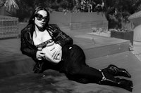 a pregnant woman in black and white sitting on a wooden deck