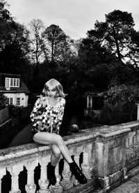 a black and white photo of a woman sitting on a railing